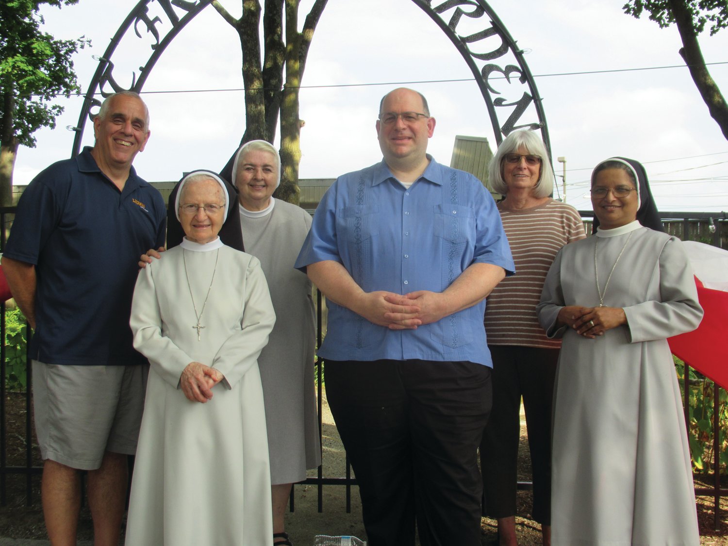 FESTIVAL FOLKS: Rev. Angelo Carusi is joined by St. Rocco’s Feast and Festival Co- chair Richard Montella, Sisters Donna, Mary Antoinette and Daisy along with Carol Blanchard outside the St. Francis Garden that is decorated with American and Italian flags in honor of this weekend’s 82nd annual fun and food fest.